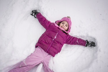 High angle portrait of happy girl making snow angel on field - CAVF54638