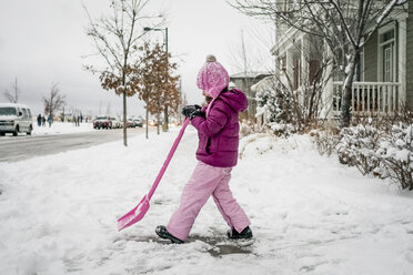 Seitenansicht eines Mädchens beim Schneeräumen mit einer Schaufel auf der Straße gegen den Himmel - CAVF54639