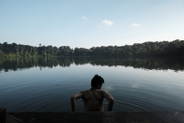 Rückansicht eines im See stehenden Mannes ohne Hemd gegen den Himmel - CAVF54640