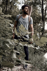 Junger Mann mit Rucksack, der wegschaut, während er im Wald steht - CAVF54652