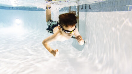 Hemdloser süßer Junge schwimmt unter Wasser im Pool - CAVF54663