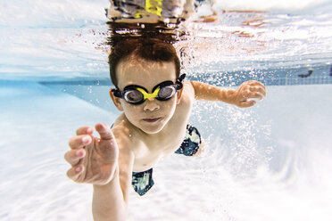 Porträt eines Jungen ohne Hemd, der in einem Pool unter Wasser schwimmt - CAVF54664