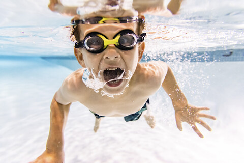 Porträt eines Jungen ohne Hemd mit offenem Mund beim Schwimmen im Pool, lizenzfreies Stockfoto