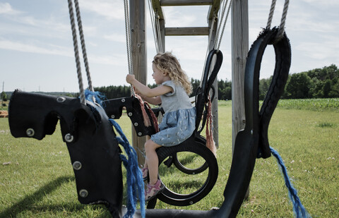 Side view of girl swinging against sky at park stock photo