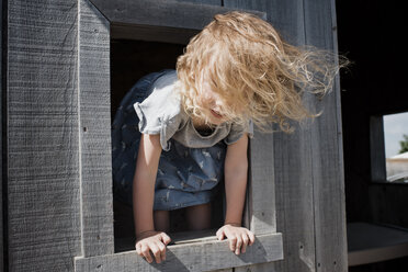 Close-up of girl peeking through wooden window - CAVF54680