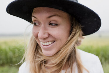 Close-up of happy woman wearing hat while standing against plants - CAVF54682