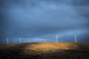 Low angle view of windmills on hill against cloudy sky - CAVF54721