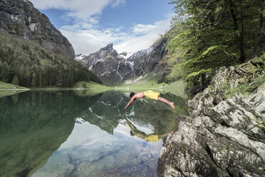 Seitenansicht eines Mannes ohne Hemd, der gegen die Berge in einen See taucht - CAVF54725