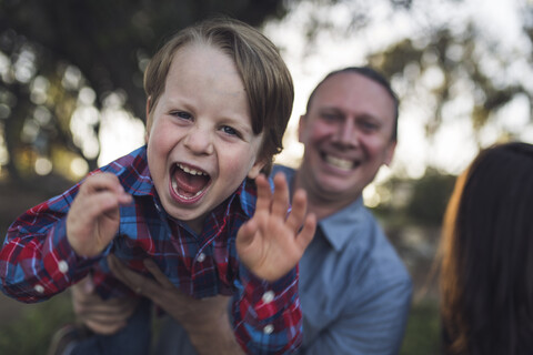 Porträt eines verspielten Sohnes, der vom Vater im Park getragen wird, lizenzfreies Stockfoto