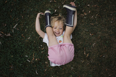 High angle view of playful girl lying on grassy field at park - CAVF54818