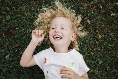 Nahaufnahme eines fröhlichen Mädchens, das auf einer Wiese im Park liegt, lizenzfreies Stockfoto