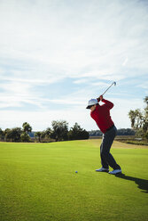 Mann in voller Länge beim Golfspielen auf einem Feld vor blauem Himmel - CAVF54836