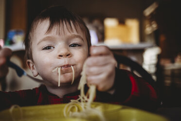 Porträt eines Jungen, der zu Hause sitzend Nudeln isst - CAVF54852