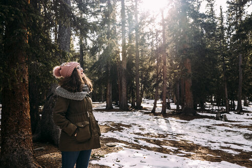 Frau trägt warme Kleidung, während sie im Winter im Wald steht - CAVF54870