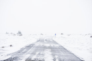 Straße inmitten eines schneebedeckten Feldes bei klarem Himmel - CAVF54928