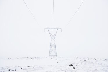 Strommast auf verschneitem Feld gegen klaren Himmel - CAVF54929