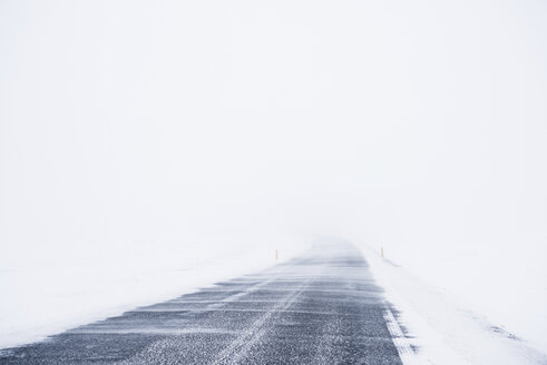 Leere Straße inmitten eines schneebedeckten Feldes bei klarem Himmel - CAVF54930