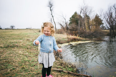 Fröhliches Mädchen hält Fisch beim Angeln am See - CAVF54949