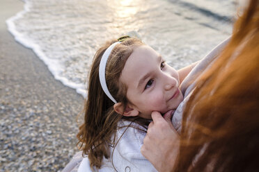 High angle view of daughter embracing mother while standing at beach during sunset - CAVF54956