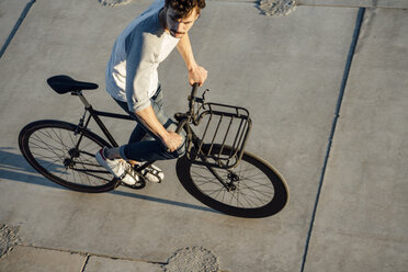 Junger Mann fährt Pendler-Fixie-Fahrrad auf Betonplatten - VPIF01034