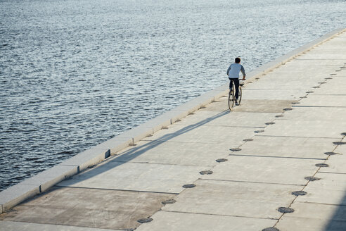 Junger Mann fährt Fahrrad auf der Uferpromenade am Flussufer - VPIF01035