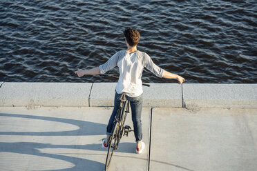 Junger Mann mit Fixie-Fahrrad macht eine Pause am Flussufer - VPIF01038