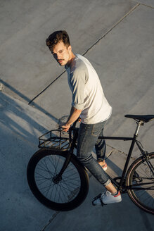 Junger Mann mit Pendler-Fixie-Fahrrad auf Betonplatten - VPIF01041