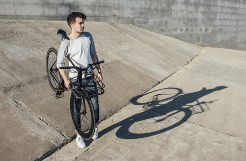 Junger Mann mit Fixie-Fahrrad an Betonwand - VPIF01075
