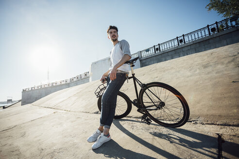 Junger Mann mit Pendler-Fixie-Fahrrad macht eine Pause an einer Betonwand - VPIF01078