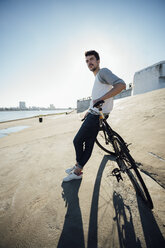 Young man with commuter fixie bike having a break at concrete wall - VPIF01079