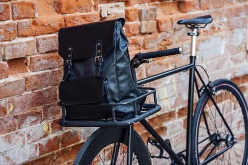 Rucksack in der Gepäckablage eines umgebauten Fixie-Fahrrads an einer Mauer - VPIF01085