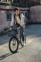 Young man with backpack riding commuter fixie bike in the city - VPIF01091