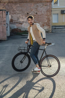 Junger Mann mit Pendler-Fixie-Fahrrad auf einem Hinterhof in der Stadt - VPIF01093