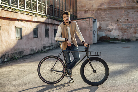 Junger Mann mit Pendler-Fixie-Fahrrad auf einem Hinterhof in der Stadt, lizenzfreies Stockfoto