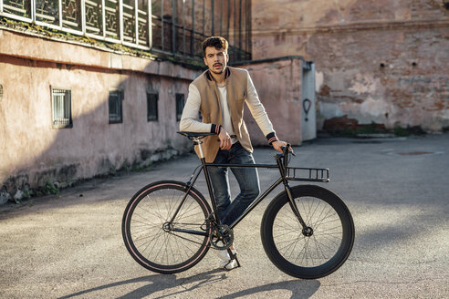 Junger Mann mit Pendler-Fixie-Fahrrad auf einem Hinterhof in der Stadt - VPIF01096