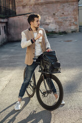 Junger Mann mit Pendler-Fixie-Fahrrad bei einer Pause in einem Hinterhof in der Stadt - VPIF01098