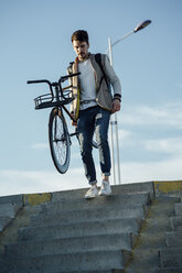 Young man carrying commuter fixie bike walking down stairs - VPIF01100