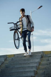 Junger Mann mit Fixie-Fahrrad geht eine Treppe hinunter - VPIF01100