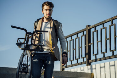 Junger Mann mit Fixie-Fahrrad geht eine Treppe hinunter - VPIF01101