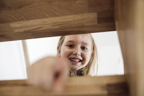 Porträt eines glücklichen kleinen Mädchens auf der Treppe zu Hause, lizenzfreies Stockfoto