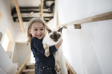 Portrait of little girl with her Siamese cat at home - KMKF00641