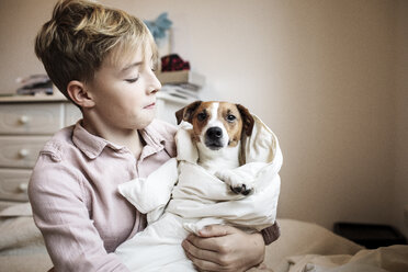 Boy with Jack Russel Terrier wrapped in blanket - KMKF00647