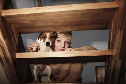 Porträt eines Jungen mit Jack Russel Terrier auf der Treppe zu Hause, lizenzfreies Stockfoto