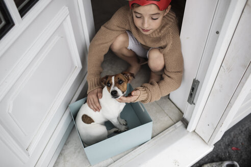 Junge mit Jack Russel Terrier, der in einem Karton am Hauseingang sitzt - KMKF00657