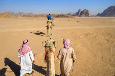 First person perspective riding camel through desert of Wadi Rum, protected desert wilderness in southern Jordan, with sandstone mountains and man riding camel in distance, Wadi Rum Village, Aqaba Governorate, Jordan - AURF07733