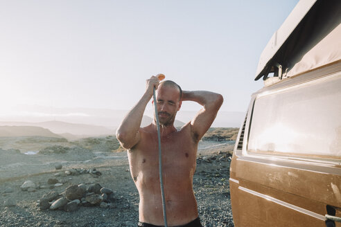 A man takes shower out of his van, Tenerife, Canary Islands, Spain - AURF07776