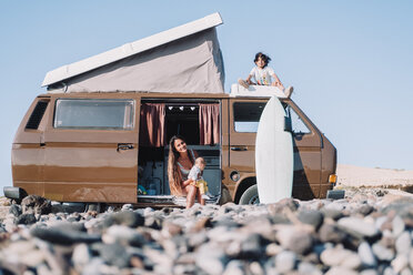 Young mother with children by vintage camper van on stony beach, Tenerife, Canary Islands, Spain - AURF07779