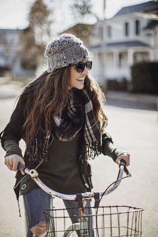 Junge Frau fährt mit dem Fahrrad durch ein Dorf, Peaks Island, Maine, USA, lizenzfreies Stockfoto