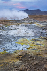 Bunt gefärbte Erde und aktive Dampfquelle mit Namafjall im Hintergrund, im Geothermalgebiet Hverarâândor Hverir am Namaskard-Pass in Island. - AURF07847
