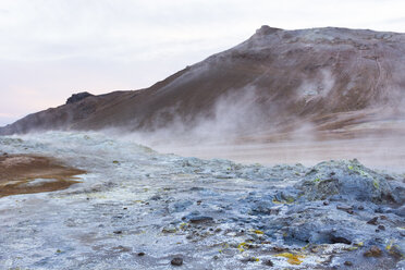 Dampfende, blau gefärbte Schlammbecken mit dem Namafjall im Hintergrund, im Geothermalgebiet Hverarâândor Hverir am Namaskard-Pass in Island. - AURF07848